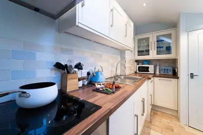 a kitchen with white cabinets and a wooden counter top at Shrimp Cottage in St Ives