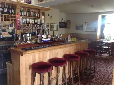 a bar with red stools in a room with a counter at The Safe Harbour Hotel in Fowey