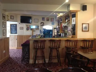 a bar in a restaurant with bar stools in a room at The Safe Harbour Hotel in Fowey