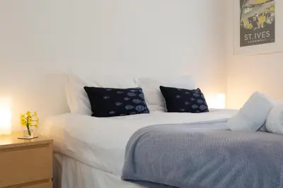 a bedroom with a large white bed with blue pillows at 35 Carrack Widden in St Ives