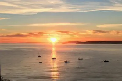 a sunset over a large body of water with boats at 35 Carrack Widden in St Ives