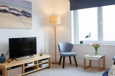 a living room with a television and a blue chair at 35 Carrack Widden in St Ives