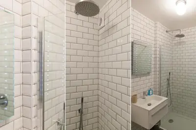 a white tiled bathroom with a sink and a shower at 21 Carthew Court in St Ives