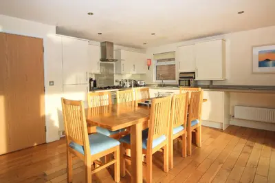 a large kitchen with a wooden table and chairs at ON-SITE WATERSPORTS family lodge in Saint Columb Major