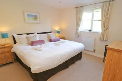 a bedroom with a large white bed with a window at ON-SITE WATERSPORTS family lodge in Saint Columb Major
