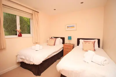 two beds in a bedroom with two windows at ON-SITE WATERSPORTS family lodge in Saint Columb Major