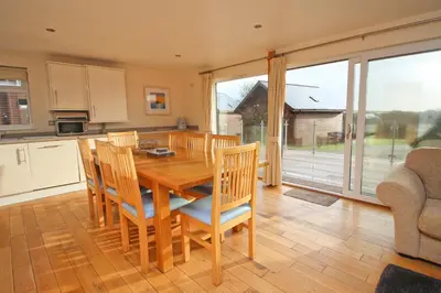 a kitchen and dining room with a wooden table and chairs at ON-SITE WATERSPORTS family lodge in Saint Columb Major