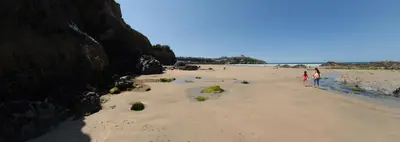 two people standing on a beach near the water at Harrington Flats in Newquay