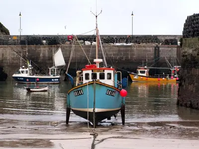 a small blue boat sitting in the water at Harrington Flats in Newquay