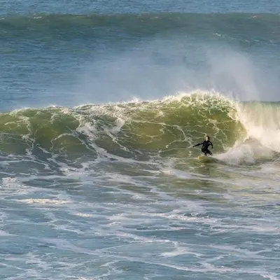 a man riding a wave on a surfboard in the ocean at Harrington Flats in Newquay