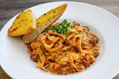 a white plate with pasta and a slice of bread at The Victoria Inn in Truro