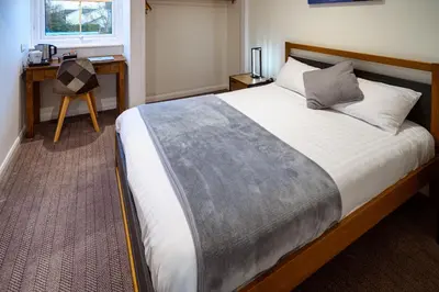a bedroom with a large bed with a desk and a window at The Victoria Inn in Truro