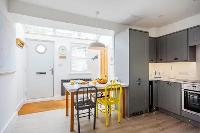 a kitchen with a table and yellow chairs in it at Seafarers, Mevagissey - Coastguard Cottage overlooking harbour in Mevagissey