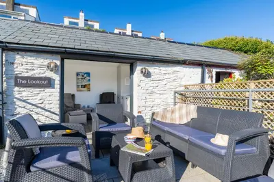 a patio with wicker chairs and a shed at Seafarers, Mevagissey - Coastguard Cottage overlooking harbour in Mevagissey