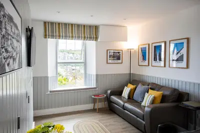 a living room with a couch and a window at Seafarers, Mevagissey - Coastguard Cottage overlooking harbour in Mevagissey