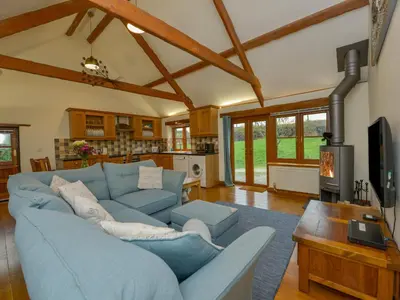 a living room with a blue couch and a tv at Hook Cottage in Looe
