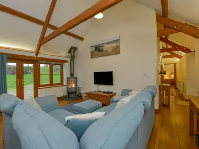 a living room with a blue couch and a tv at Hook Cottage in Looe
