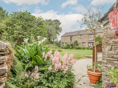 a garden with pink flowers in front of a house at Erin Cottage in Pelynt
