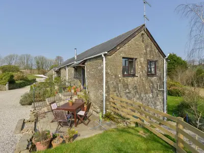 a stone cottage with a table and chairs in front of it at Erin Cottage in Pelynt