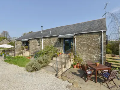 a stone house with a table and chairs in front of it at Erin Cottage in Pelynt