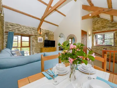 a living room with a table and a blue couch at Erin Cottage in Pelynt
