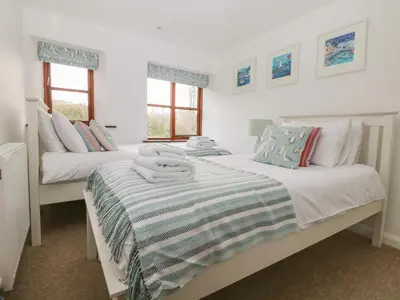 a bedroom with two beds with towels on them at Erin Cottage in Pelynt