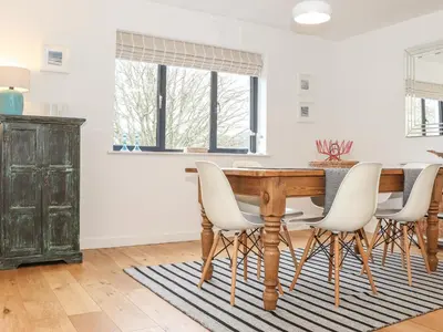 a dining room with a wooden table and white chairs at Garden House in Gorran Haven