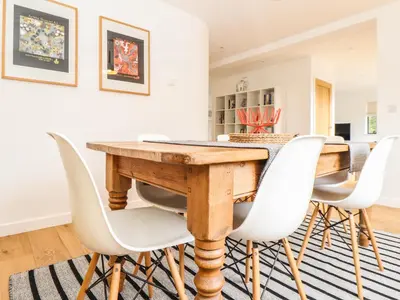 a dining room with a wooden table and white chairs at Garden House in Gorran Haven