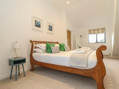 a bedroom with a bed with green and white pillows at Garden House in Gorran Haven