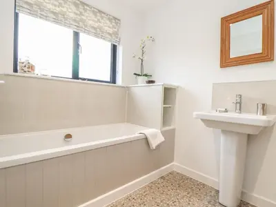 a bathroom with a bath tub and a sink at Garden House in Gorran Haven