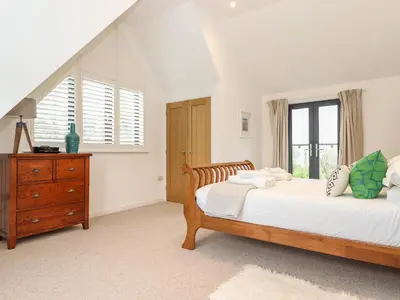 a bedroom with two beds and a dresser and a window at Garden House in Gorran Haven