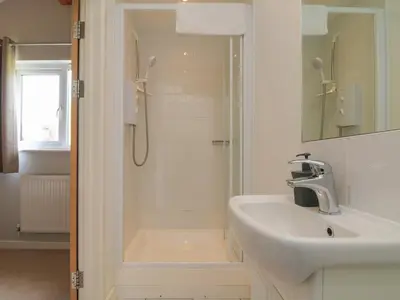 a white bathroom with a shower and a sink at Lodge Sixty Six in Saint Columb Major