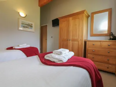 a bedroom with two beds and a dresser and towels at Lodge Sixty Six in Saint Columb Major
