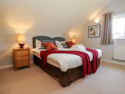 a bedroom with a bed with a red blanket on it at Lodge Sixty Six in Saint Columb Major