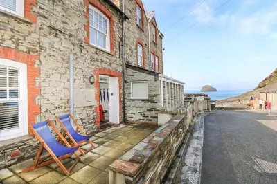 two blue chairs sitting outside of a stone building at Rock House in Tintagel