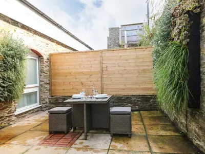 a patio with a wooden fence and a table at Rock House in Tintagel