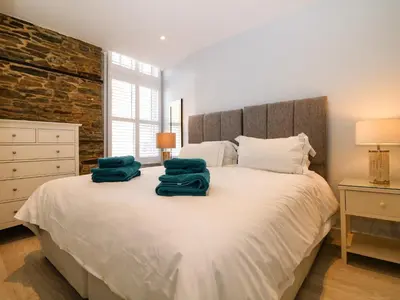a bedroom with a white bed with two green towels on it at Rock House in Tintagel