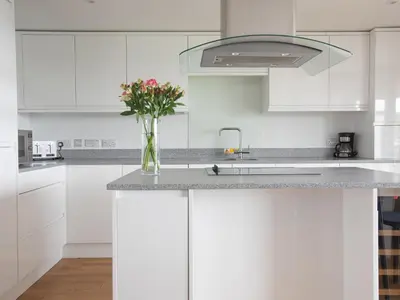 a white kitchen with a vase of flowers on a counter at Onshore 6 - Newquay Towan Beach View in Newquay