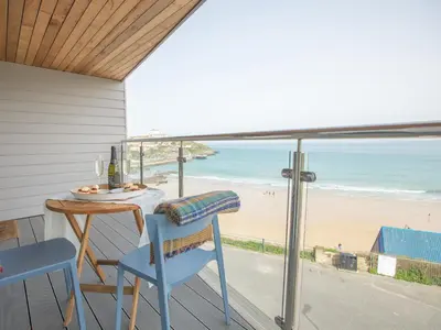 a balcony with a table and chairs and a view of the beach at Onshore 6 - Newquay Towan Beach View in Newquay