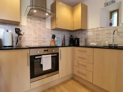 a kitchen with wooden cabinets and an oven at Cawsand in Saltash