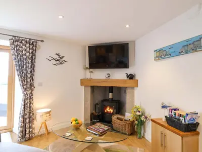 a living room with a fireplace and a tv on the wall at Cawsand in Saltash