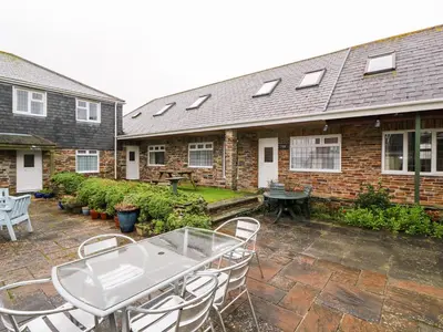 a patio with a table and chairs in front of a house at Tynk in St Merryn