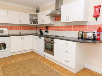 a kitchen with white cabinets and a black counter top at Tynk in St Merryn
