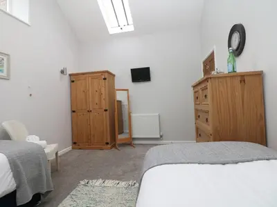 a bedroom with a bed and a wooden dresser at Hazel Barn in Falmouth