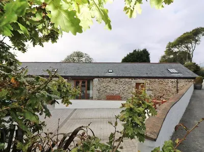 a stone house with a black roof at Hazel Barn in Falmouth