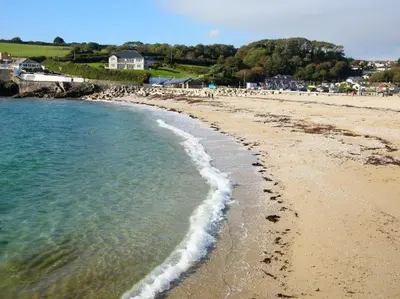 a beach with footprints in the sand and water at Hazel Barn in Falmouth