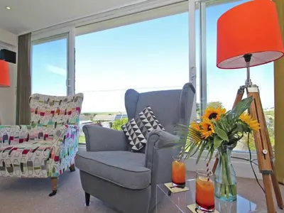 a living room with a chair and a table with a lamp at Seagrass in Newquay