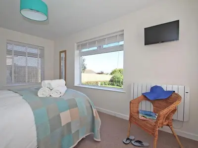 a bedroom with a bed and a tv and a window at Seagrass in Newquay