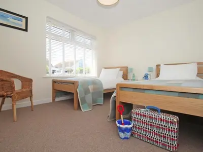 a bedroom with two beds and a desk and a window at Seagrass in Newquay