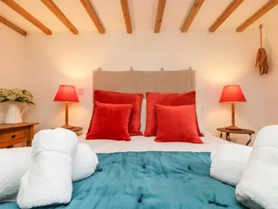 a bedroom with a bed with red pillows and two lamps at Hay Loft in Camborne